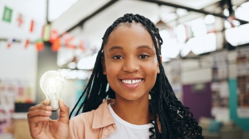 Image captures student holding a light bulb, as to connotate having a great idea.