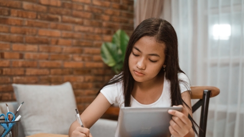 Image of a high school student studying at her dining room table.