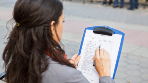 Women filling out paper survey on clipboard