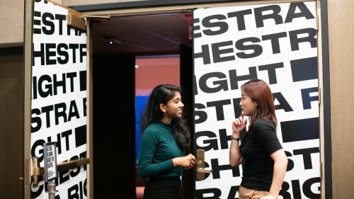 Two students talking in front of theatre doors