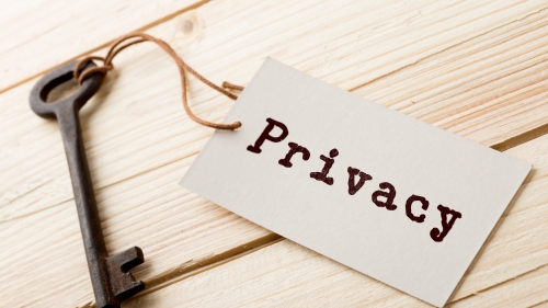 Image captures a photo of a key tied to string and rectangular piece of paper which reads "Privacy"