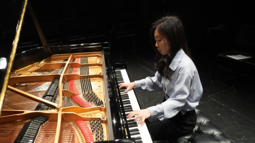 Woman playing grand piano with a view of the inside of the piano