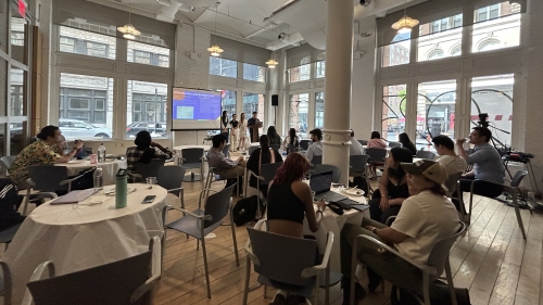 Students in the Pless Lobby watch a presentation from other students