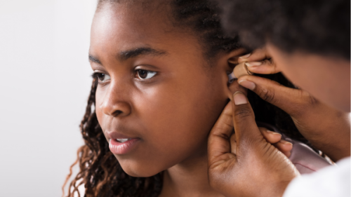Doctor putting hearing aid in child's ear