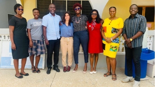 Photo of Javi in the middle, wearing blue top and beige pants, standing with 7 people from the United Way Ghana Team 