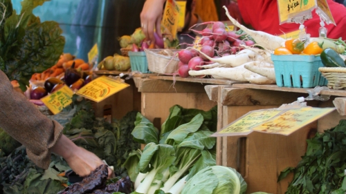 Market stand with produce like peppers, cabbage, and leeks