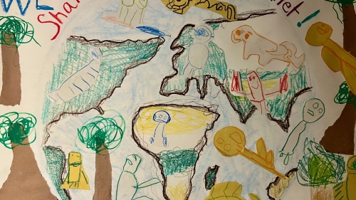 Image captures elementary student produced Earth Day poster. The crayon drawn poster features tall trees with green leaves, a hand drawn rendering of the United States, the continent of Africa, Europe, and Japan. While oceans do not exist between the continents in this rendering, sketches of animals such as dogs and cats exist in there place. Along with text statements that read, "We Share", "Save the Planet", and "Help the Planet". 