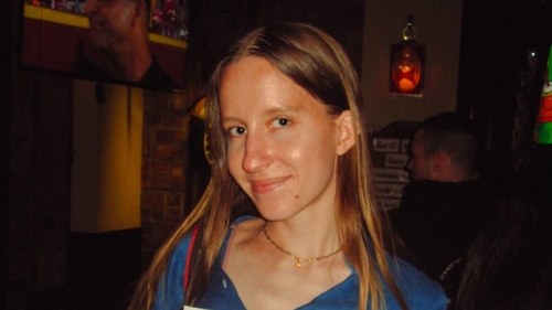 Taylor, in a blue blouse and jeans, holds an issue of Copy magazine showing a pink horse on the cover