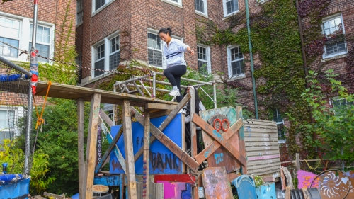 A student climbs on a wooden playscape
