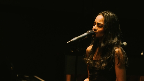 Student singing on stage in front of piano