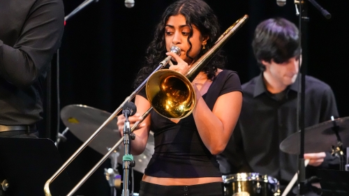Female student playing trumbone on the stage with jazz band