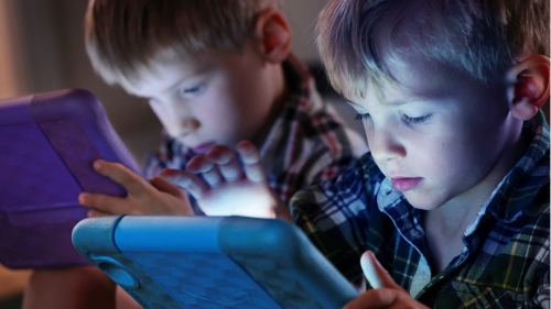 Two children use iPad tablets.
