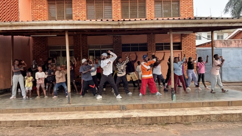 A group of people, from children to adults, stands in a pose under a large awning