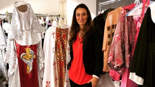 Costumer designer standing in front of racks of costumes