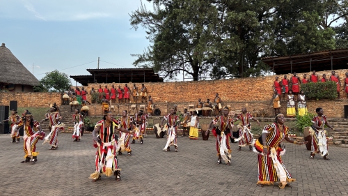 A group of people in red, yellow, and white costumes dances in a large courtyard