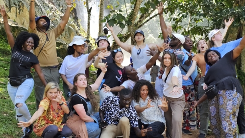 A group of people does silly poses and faces in front of a waterfall