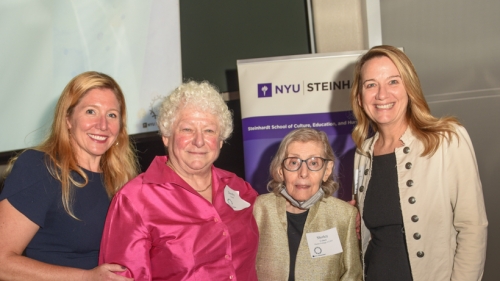 Image captures the senior members of NYU's ASD Nest Support Team standing together to accomodate a photo at an awards ceremony. From left to right, Executive Director, Allison Graham Bell wearing green, Dorothy Siegel wearing pink,  Dr. Shirley Cohen wears gold colored jacket and eye-glasses, and Kristie Patten, ASD Nest PI on the end, wearing khaki colored jacket.
