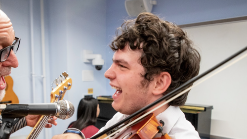 Teacher and student singing and laughing playing guitar and violin