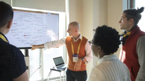 Four people looking at a smart board. 