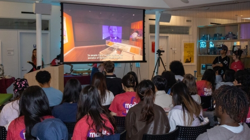 A group of people sits facing a screen