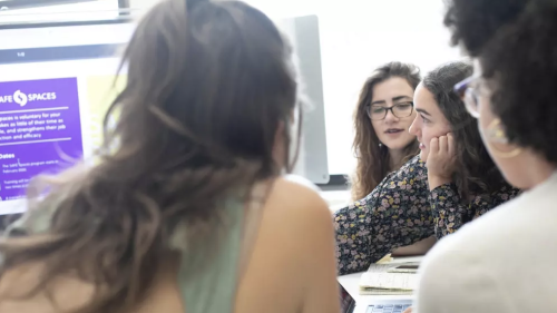 Four students looking at computer screen with Safe Spaces detailed on it