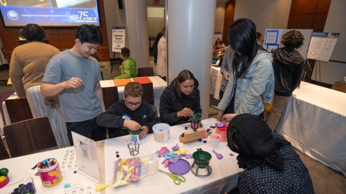 People gather around a table to build objects