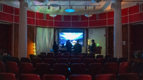 A dark room with a screen in the front showing an image of mountains