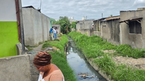 Houses along a small canal in Tanzania. A few people stand along the canal.