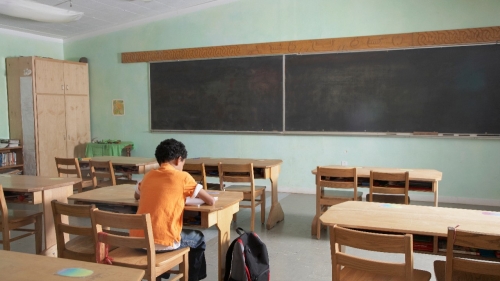 A student sits alone in a classroom
