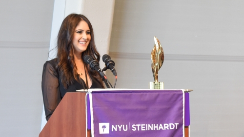 Susan Aryan Antolin stands at a podium with her award