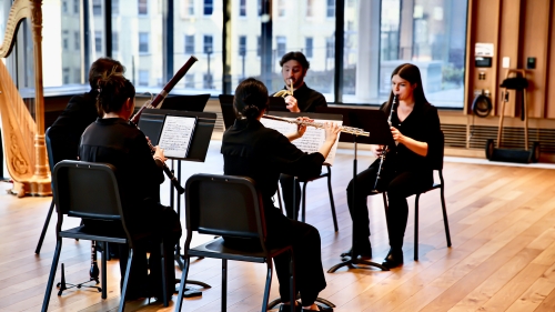 Woodwind students playing instruments in large rehearsal room