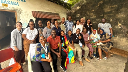 A group of students and community members smiles and poses for a photo outside.
