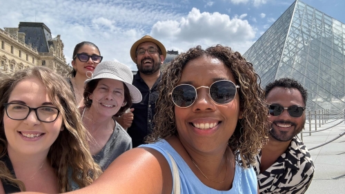 A group of teachers poses for a selfie in front of the Louvre in Paris