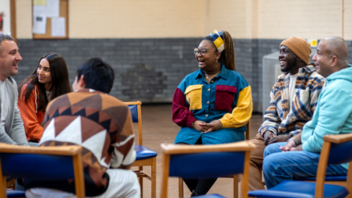 Group of people smiling and sitting on chairs in a circle 