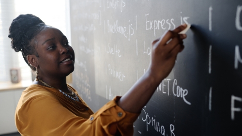 Black teacher writing on board