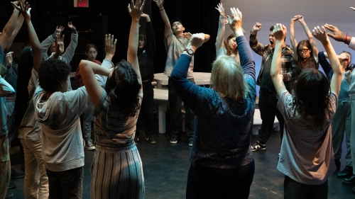 Circle of students dancing with arms extended over their heads