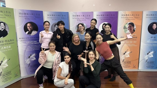 Deborah Damast and a group of students pose for the photo in front of event posters