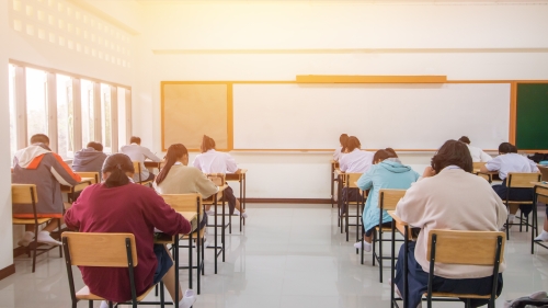 Several rows of students sit at desks and focus on their work.
