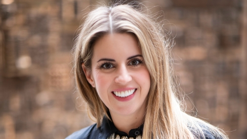 Alix is looking into the camera smiling, she's wearing a black blouse