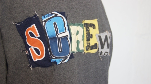 Close up image of a t-shirt with letters that spell out the word "screw"