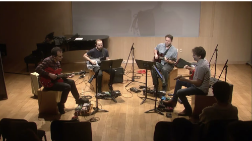 Four electric guitar musicians sitting in circle playing music