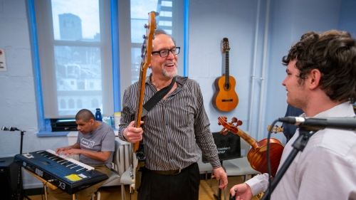 Prof Alan Turry holding guitar laughing with student