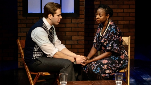 A couple formally dressed sitting and holding hands on stage