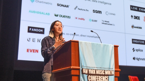 Student at podium with a list of music vendors behind her 