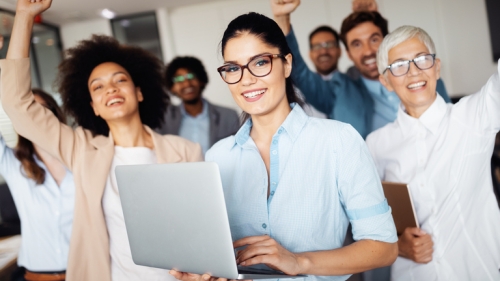 Photo of excited people, one holding a laptop