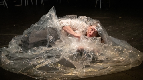 Student lying on floor covered in plastic