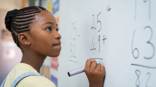 Black girl solving a math problem on a white board