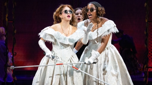 Three singers pretending to be blind while they sing. All three have on long with dresses.