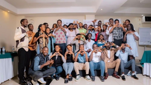 A large group of people poses for the photo holding up hearts with their hands.