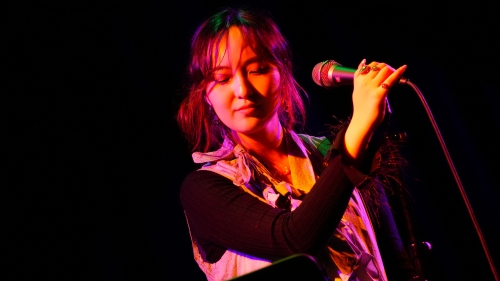 Student at Microphone in pink lighting